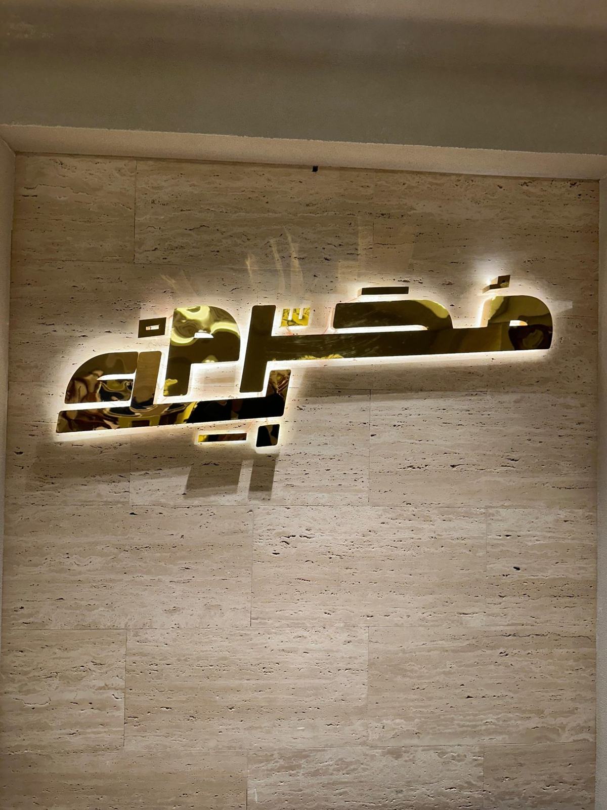 شعار محرم بك المضيء على جدار من الترافرتين